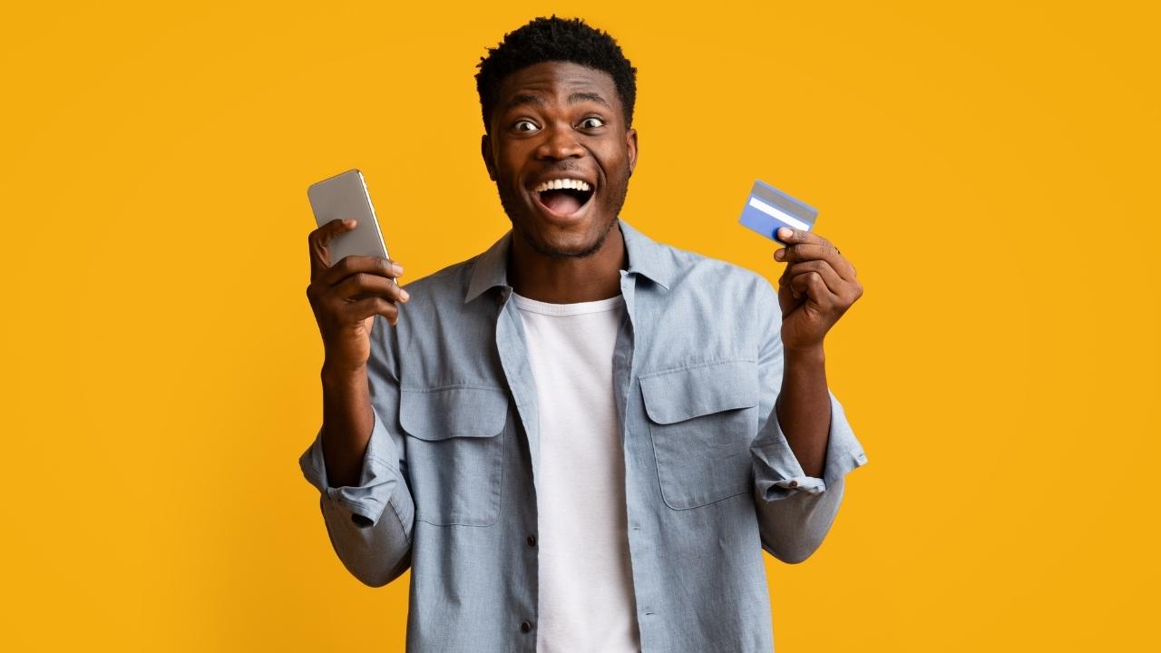 Give cash. Man holding Dollars and Phone. Surprised man face Yellow background.